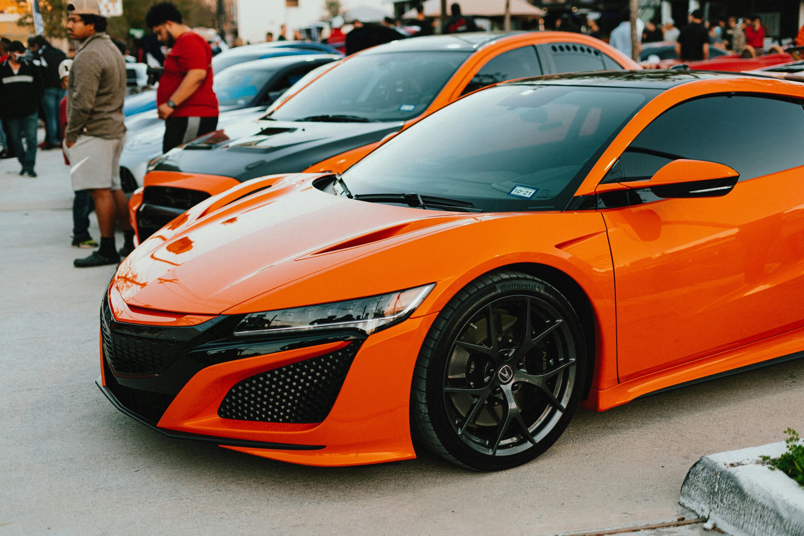 A striking orange supercar parked at an outdoor car show, drawing attention with its sleek design.